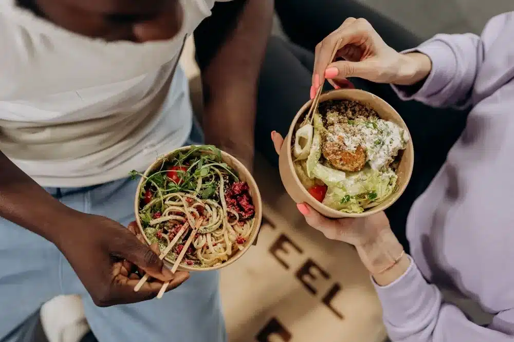 Alimentos que remineralizan el esmalte Dos personas sostienen boles de comida saludable rica en vitaminas y calcio para el esmalte dental